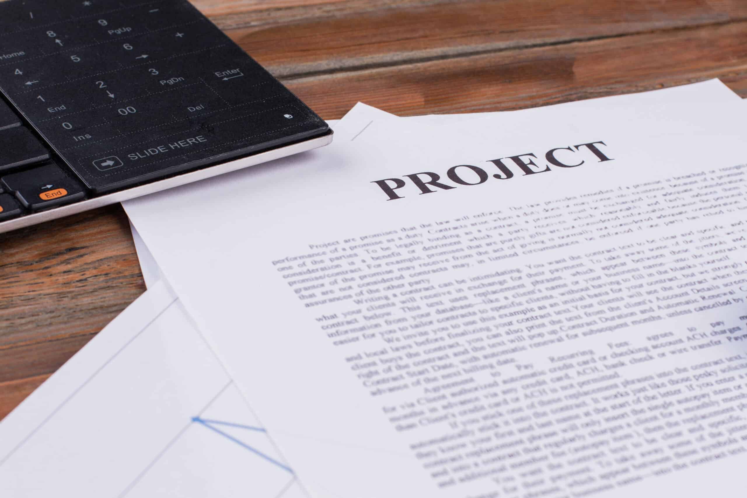 Project documents and computer keyboard showing grant application development and competitive strategy planning for federal and state funding programs