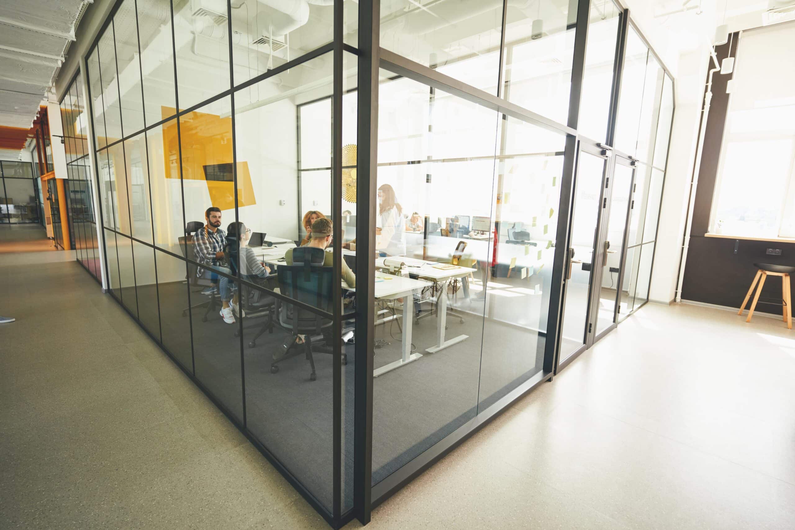 Modern business incubator workspace showing entrepreneurs collaborating in shared office environment with computers and meeting areas